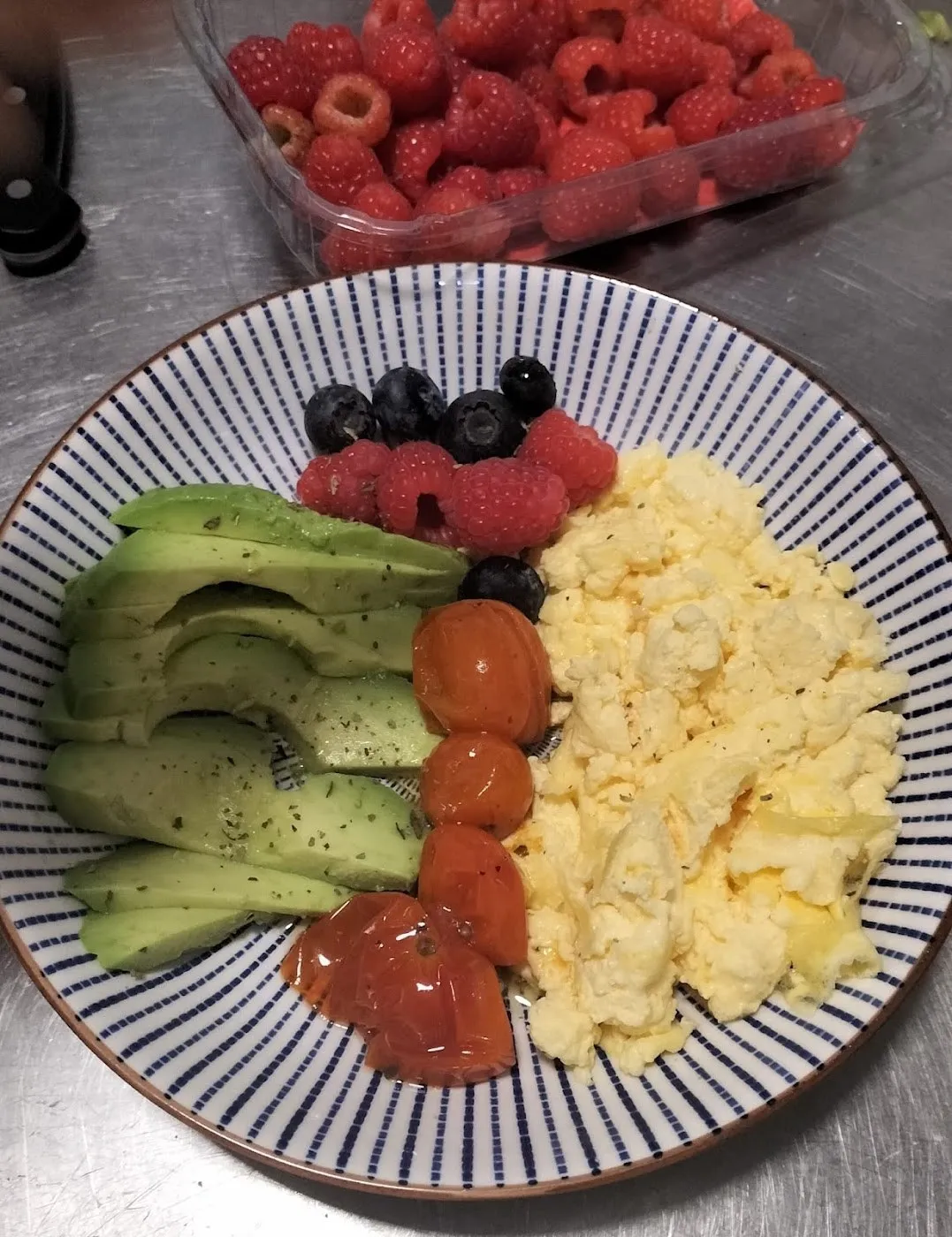 Huevos revueltos con aguacate, tomate y frutos rojos